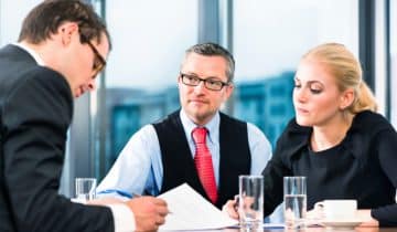 Two business men and one business woman reviewing a contract