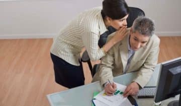 business woman whispering to business man