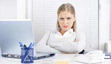 Unhappy woman seated with arms crossed and furrowed brow