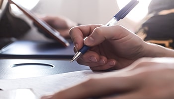 Hand holding pen with paper